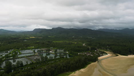 Estuary-river-sandy-ocean-beach-by-shrimp-farm-ponds-and-mountains,-khao-lak-thailand