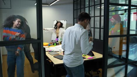 happy colleagues dancing around table in office