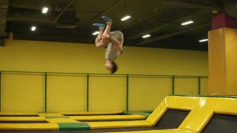 athletic male performs back double somersault flawlessly, jumping on trampoline.