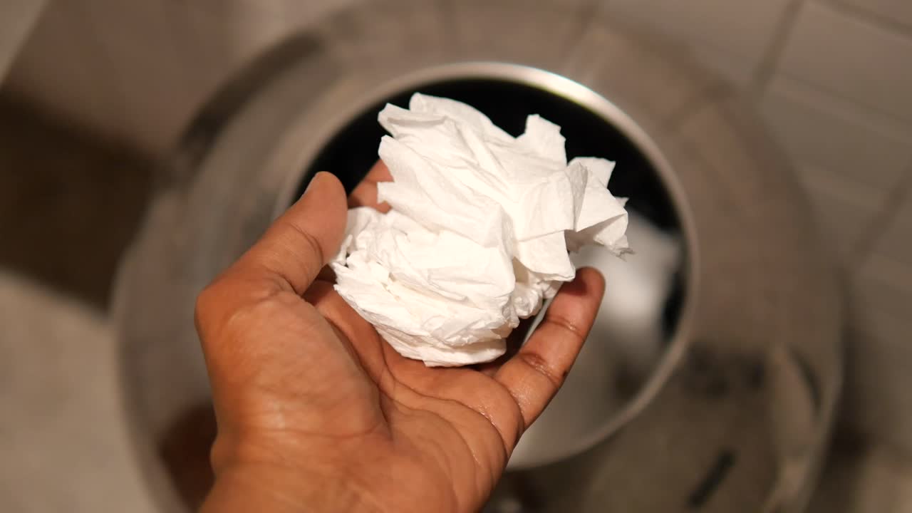 Hand holding tissue near a metal container