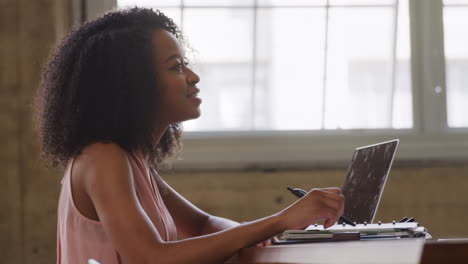 Side-view-of-black-businesswoman-talking-at-an-office-desk