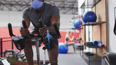 hombre afroamericano con máscara facial haciendo ejercicio en el gimnasio