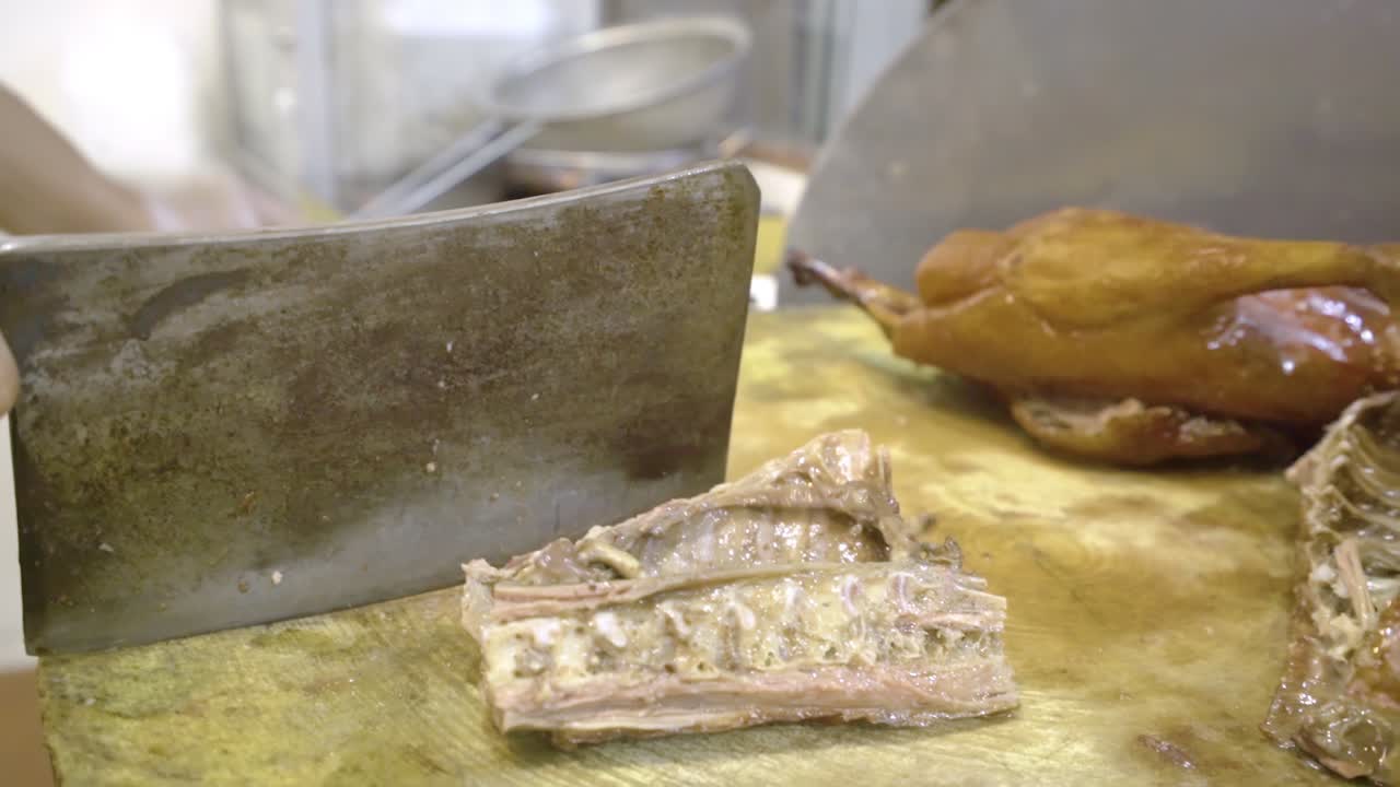 Kitchen Worker Chopping Roasted Goose On The Wooden Chop Board With A Butcher's Knife In Guangzhou, China - close up