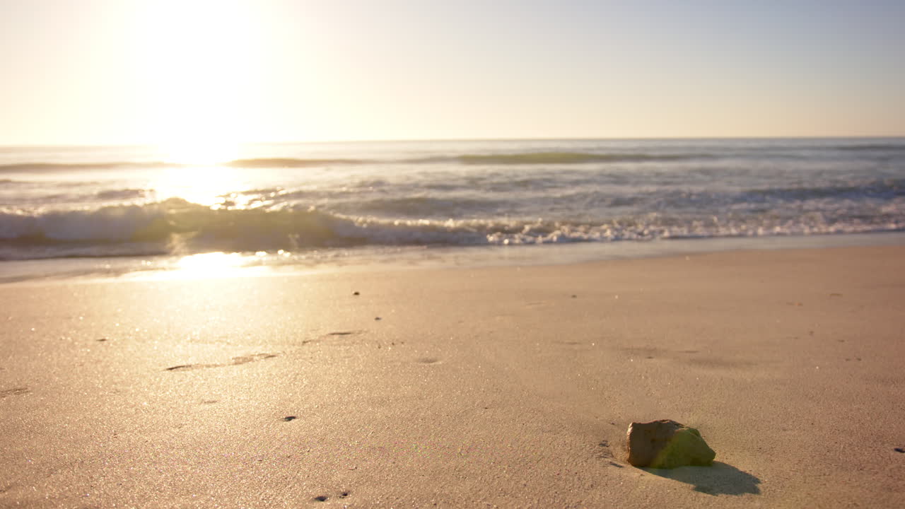 일몰은 조용한 해변에 따뜻한 빛을 고, 배경에는 부드러운 파도가 있습니다.