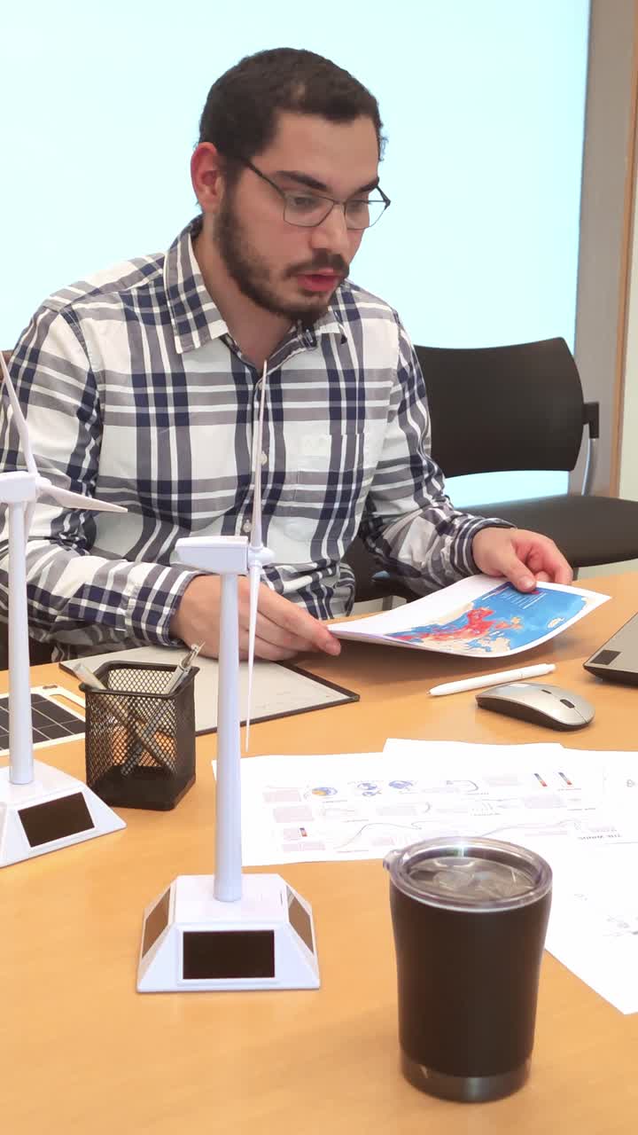 Young Architect Reviewing Project Documents with Wind Turbine Models