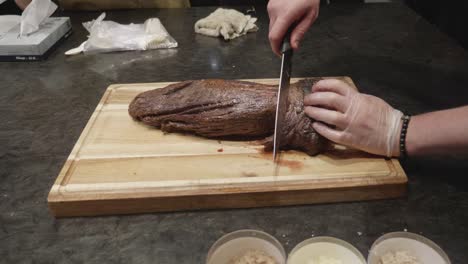 chef cuts freshly grilled beef fillet on wooden cut board at meat tasting event