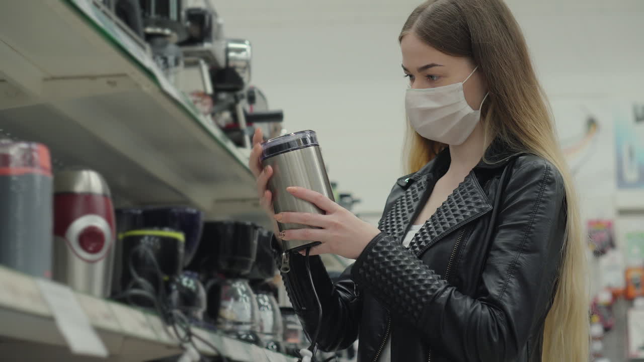 женщина, покупающая кухонные приборы в маске