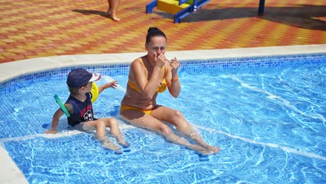 family relaxing in pool. mother with son relaxing in swimming resort pool