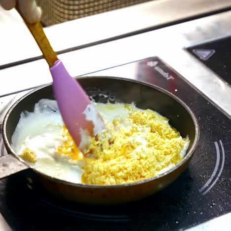 Cooking food in a frying pan. Chef is frying tasty dish in white sauce and mixing it with a scapula. Cooking delicious meal in a restaurant