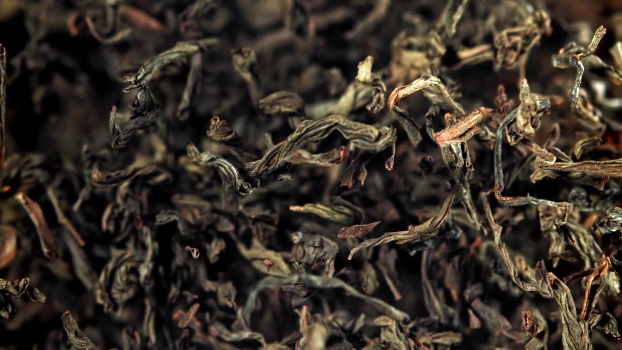Dried Tea Leaves Falling in Slow Motion on Black Background