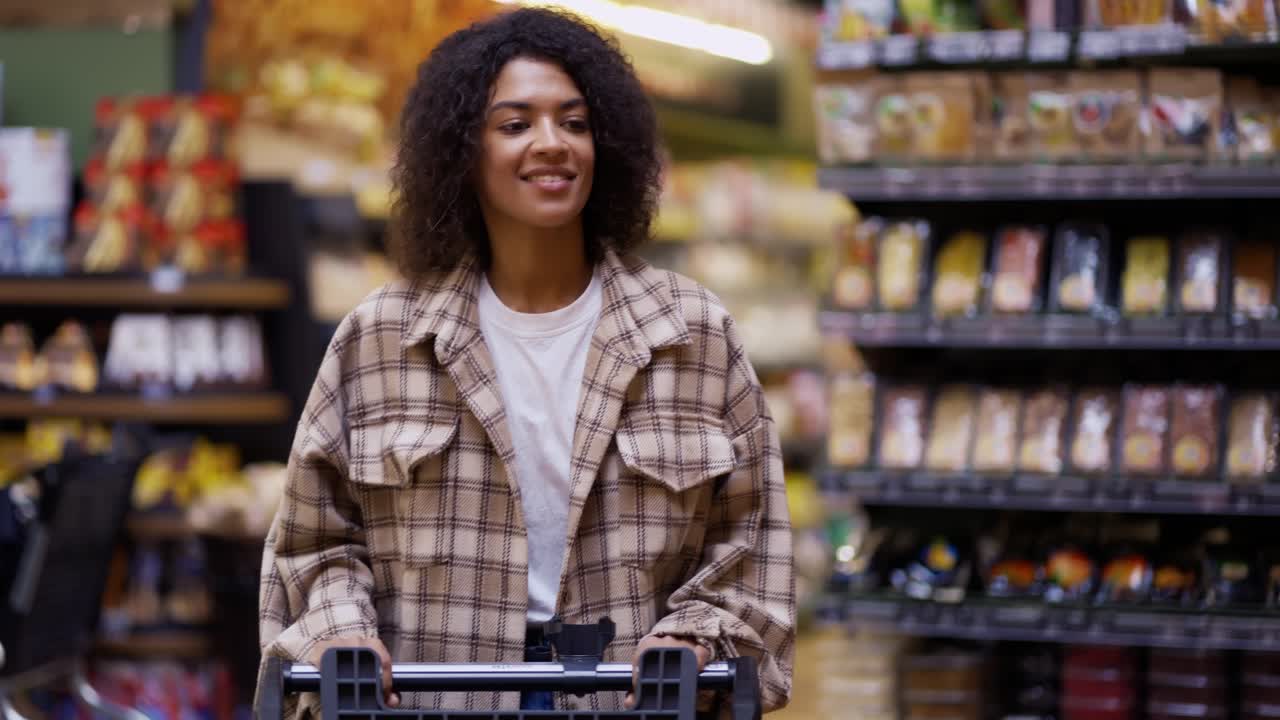 Portrait of an african american woman walks through supermarket with cart