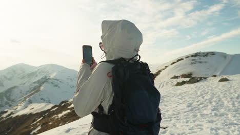 woman hiker taking picture of mountains with her smartphone, tatra mountains in europe - medium shot