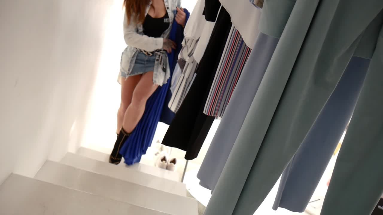 una hermosa joven morena camina a mitad de camino por los escalones de una boutique de moda y se detiene para mirar un estante de ropa mientras compra