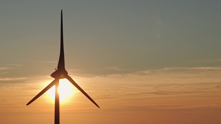 Minimalistische Windturbinensilhouette unter einem warmen Sonnenuntergangshimmel