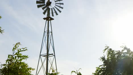 la inclinación lenta de la vieja bomba de agua de molino de viento oxidado en tierras de cultivo