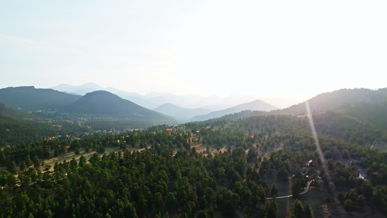 Drone establishing pullback of Estes Park, sunflare over mountain roads and fall foliage in vibrant valley
