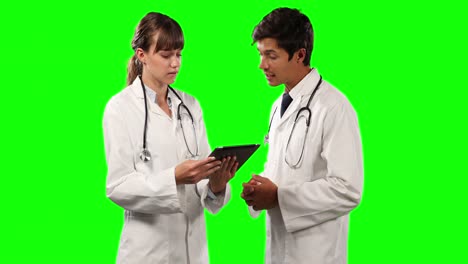 Side-view-of-doctors-discussing-and-holding-a-digital-tablet-with-green-screen