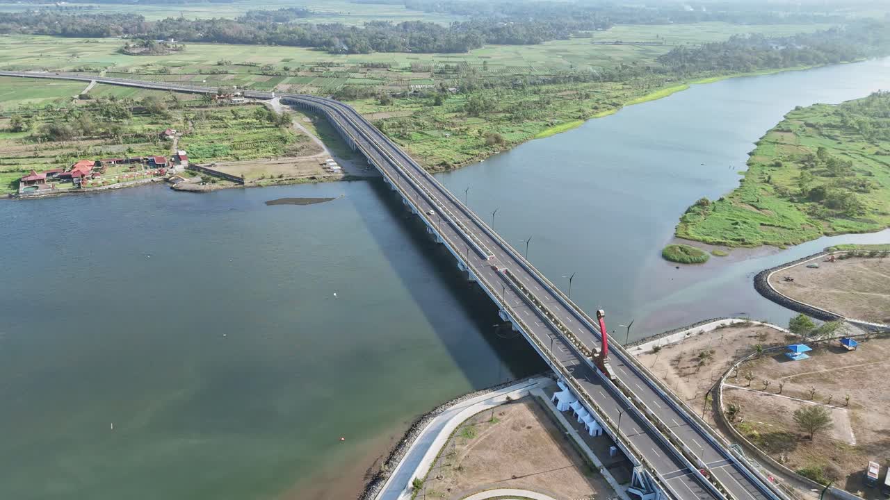 Aerial view of white car crossing big bridge on the big river. Bridge on rural Indonesia. Kretek II Bridge, Opak River. 4K drone shot.