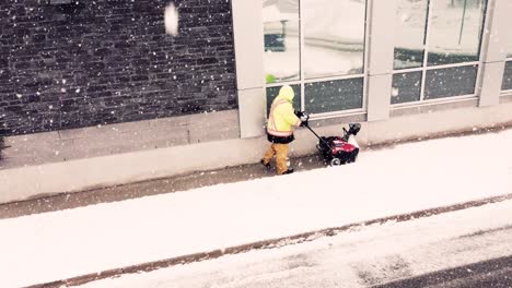 hombre limpiando la carretera con una máquina durante una nevada