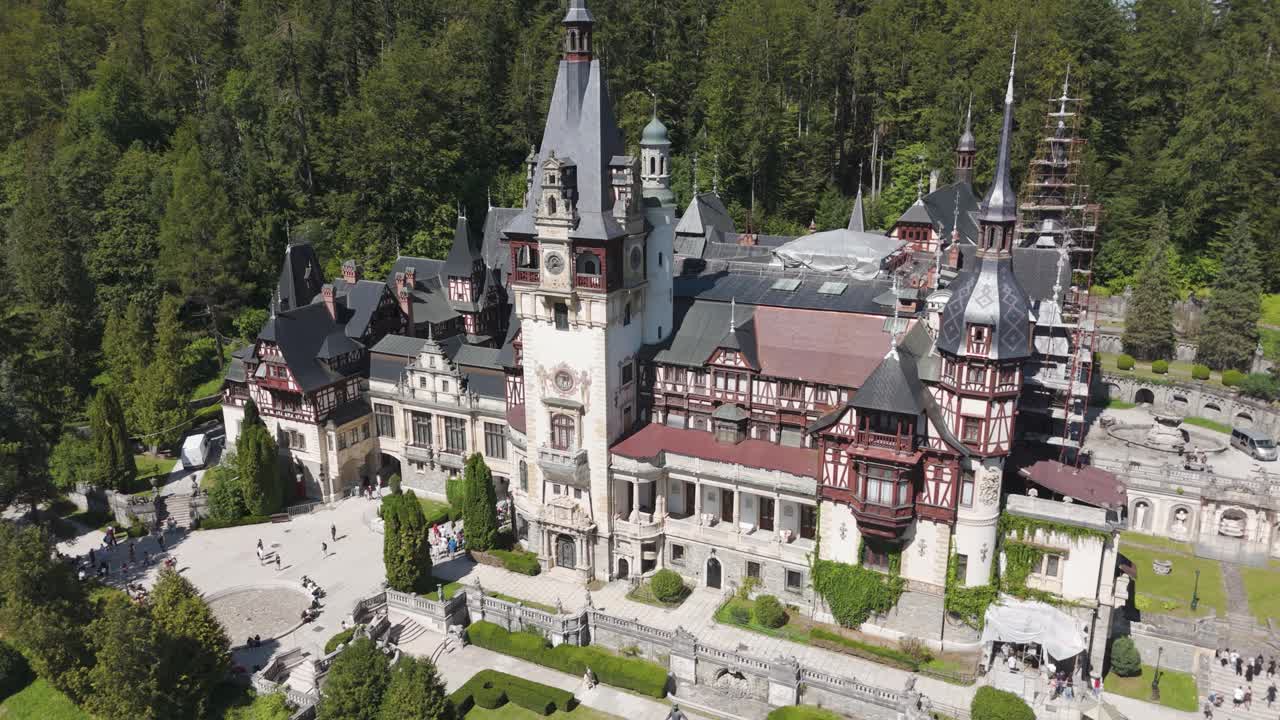 Wide pullback shot of Peleș Castle, highlighting the full extent of the palace and forest scenery