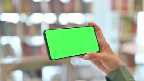 vista trasera de una mujer joven viendo un teléfono inteligente con pantalla cromada