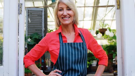 mature woman standing at the entrance of greenhouse