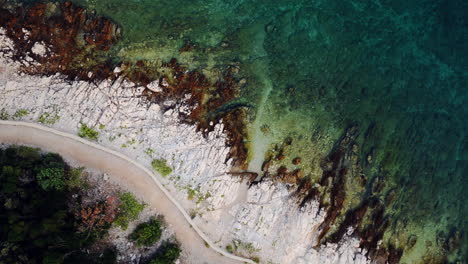 Drone-top-down-view-across-rocky-rugged-shoreline-coast-of-Slatina-beach-Croatia