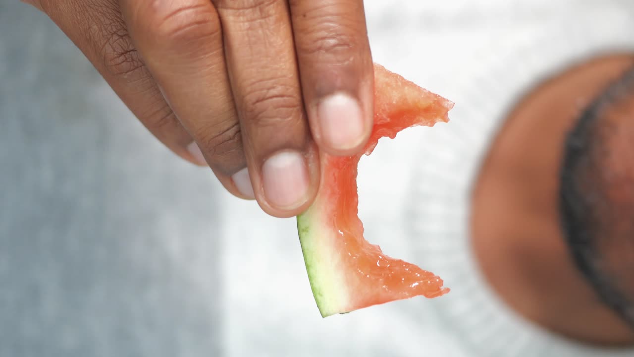 Close-up of a person holding a bite of watermelon