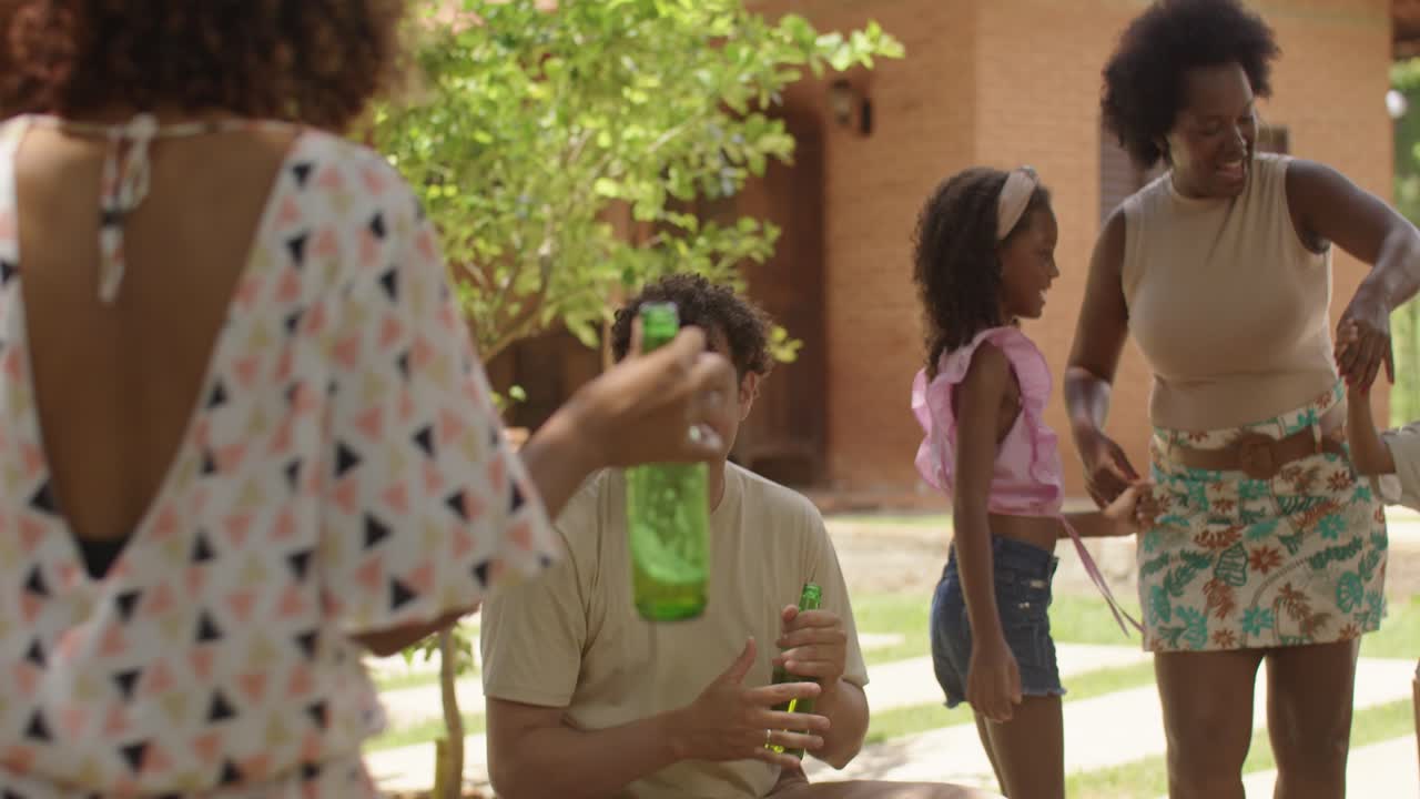 People enjoying an outdoor backyard party with dancing and drinks