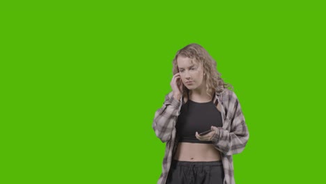 Studio-Shot-Of-Young-Woman-Listening-To-Music-On-Mobile-Phone-And-Dancing-Against-Green-Screen-3