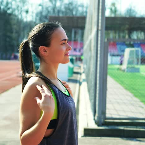 attractive woman with a beautiful slender figure doing a warm-up on the stadium running track