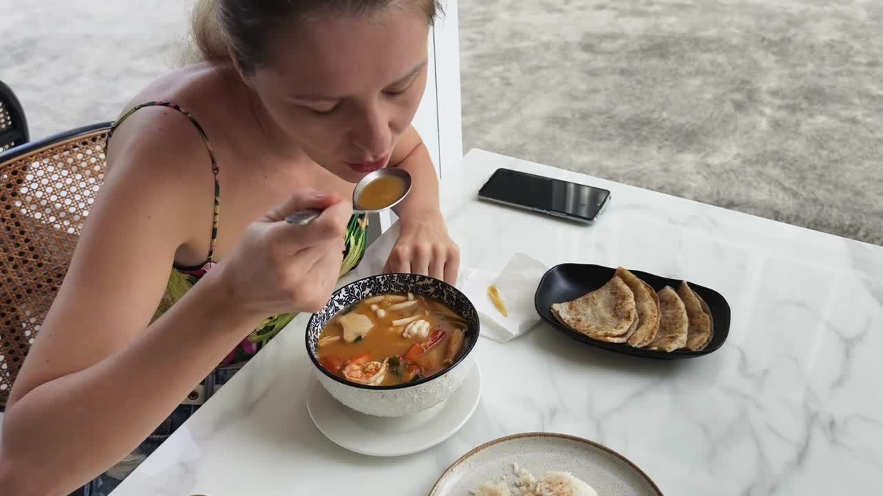 mujer comiendo sopa de tom yum