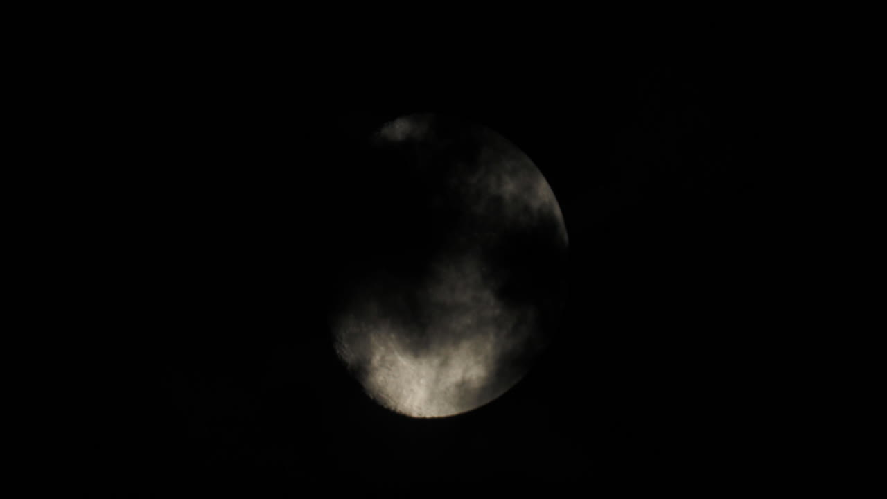 Moon partially obscured by clouds at night