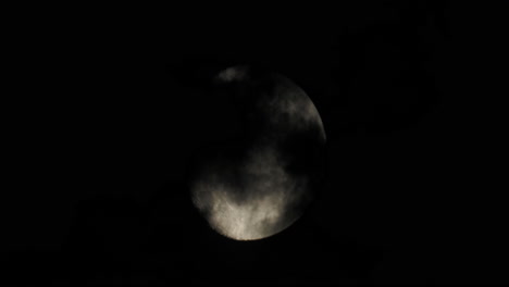 moon partially obscured by clouds at night