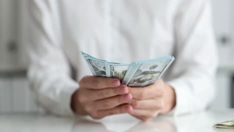 hombre de negocios con billetes de cien dólares en las manos en un primer plano en el lugar de trabajo