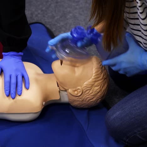 training reanimation procedure on a mannequin. people use breathing apparatus on a dummy's face during practice course. training for giving first aid to a patient.