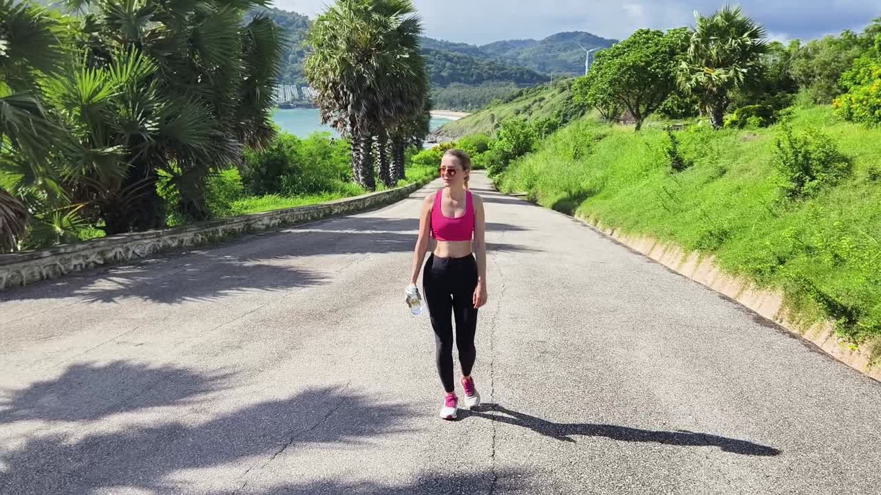 mujer caminando en un camino soleado con vista al océano