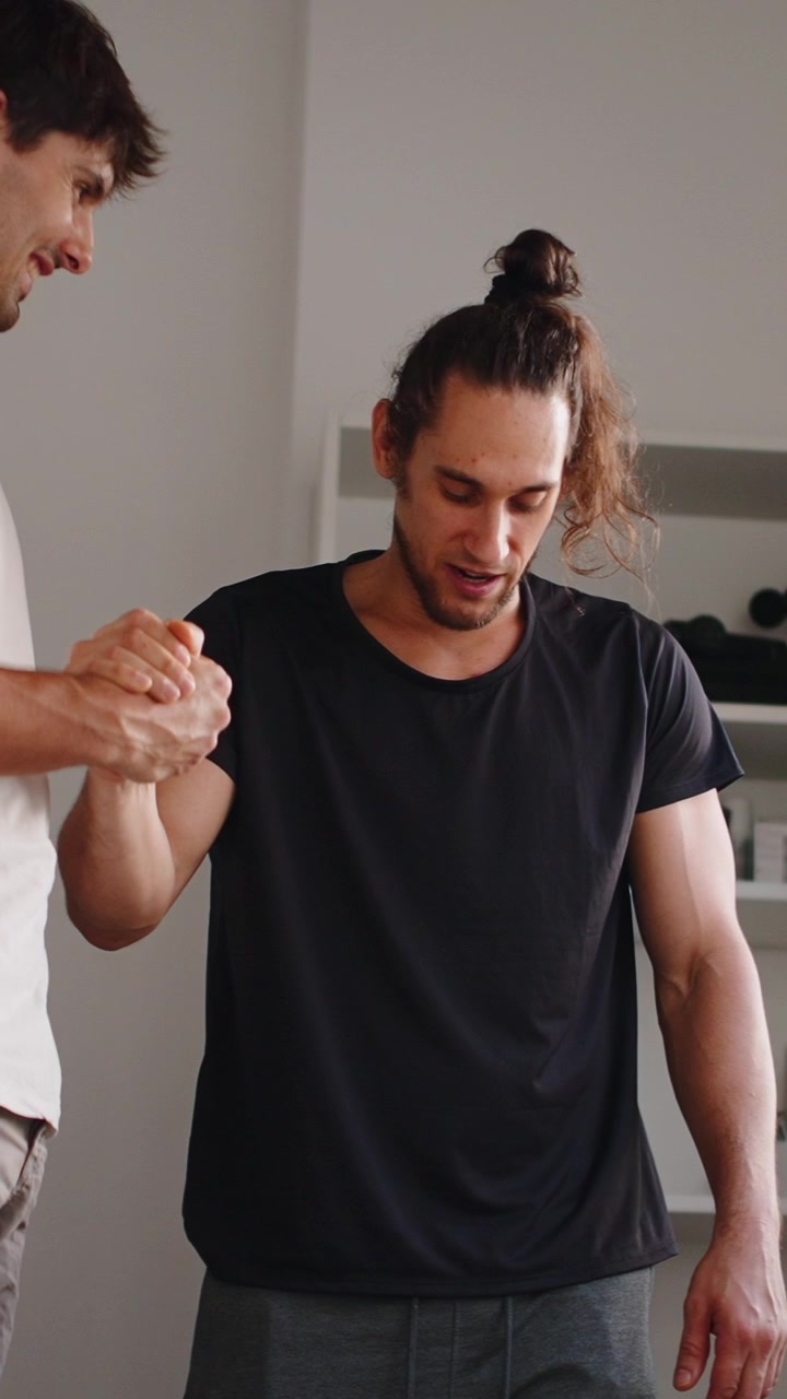 Physical Therapist Assisting Patient with Arm Exercise in Clinic
