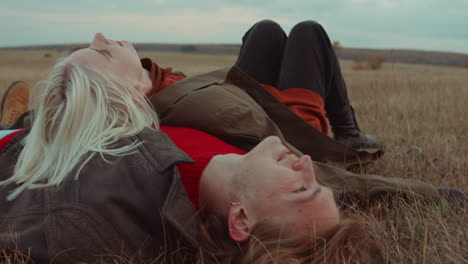 woman falling down and lying with boyfriend on autumn field