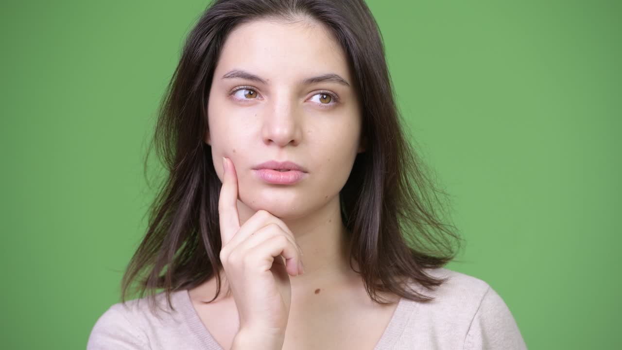 joven hermosa pensando contra el fondo verde