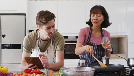 Vídeo-De-Una-Pareja-Feliz-Y-Diversa-Preparando-Comida-Junto-Con-Una-Tableta-Y-Vino