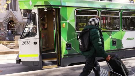 individuals boarding a green tram in melbourne