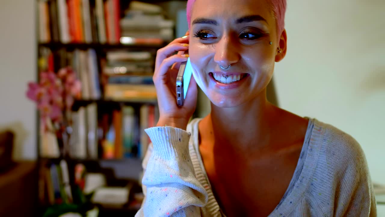 mujer de cabello rosa hablando por teléfono móvil en casa 4k