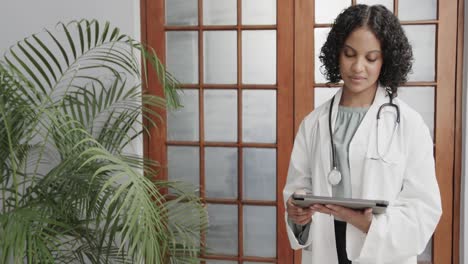 Portrait-of-biracial-female-doctor-wearing-lab-coat,-using-tablet,-copy-space,-slow-motion