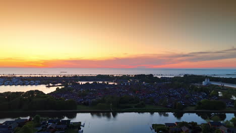 sunset over dutch lakeside. vibrant sunset paints the sky over a serene lakeside area in the netherlands with reflections on calm waters