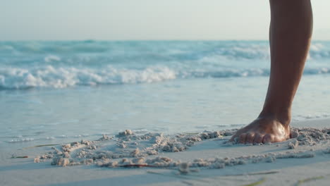 Unerkennbares-Mädchen,-Das-Auf-Sand-Zeichnet.-Unbekannte-Frau,-Die-Sich-An-Der-Küste-Aufhält.