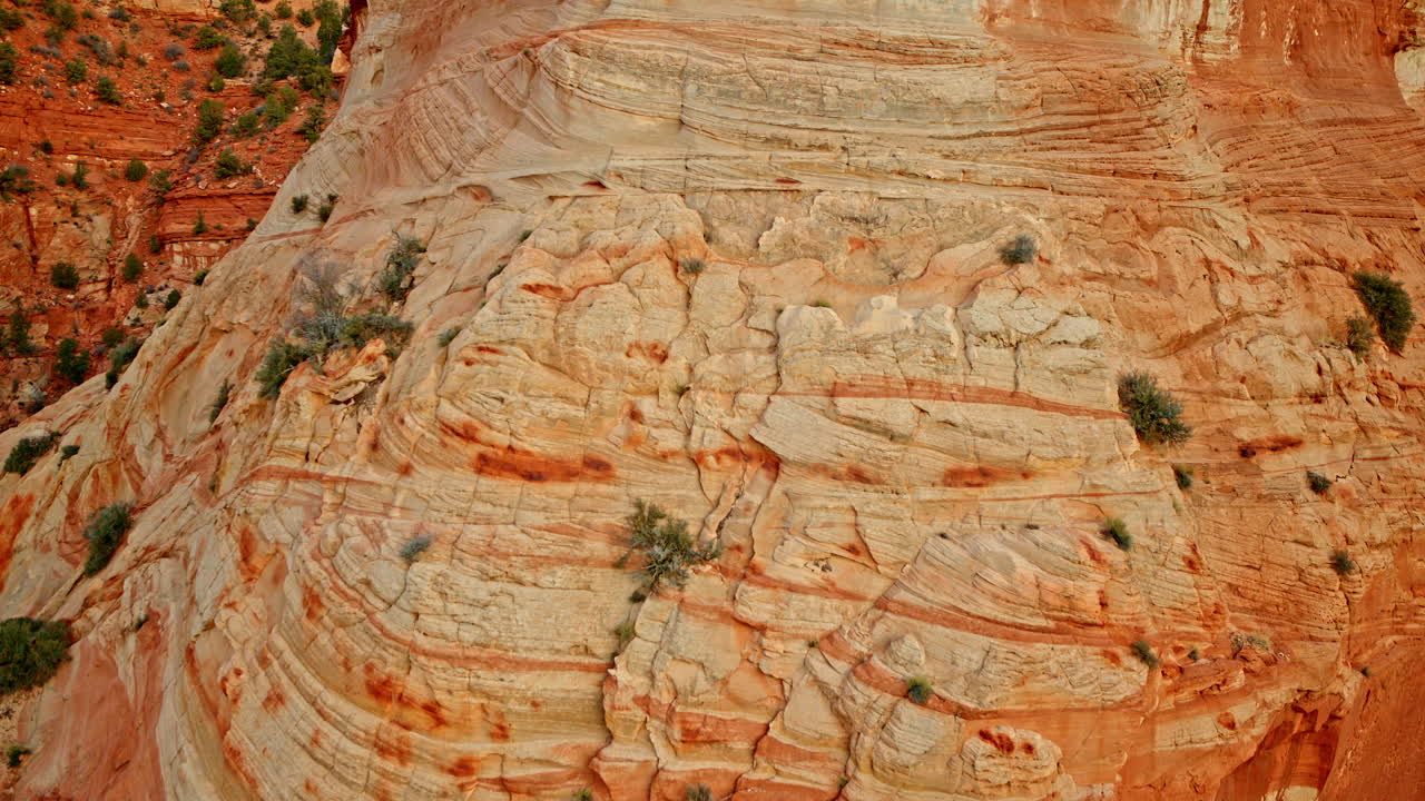 Drone flies across fascinating sculptural formations in the vivid red canyon wall.