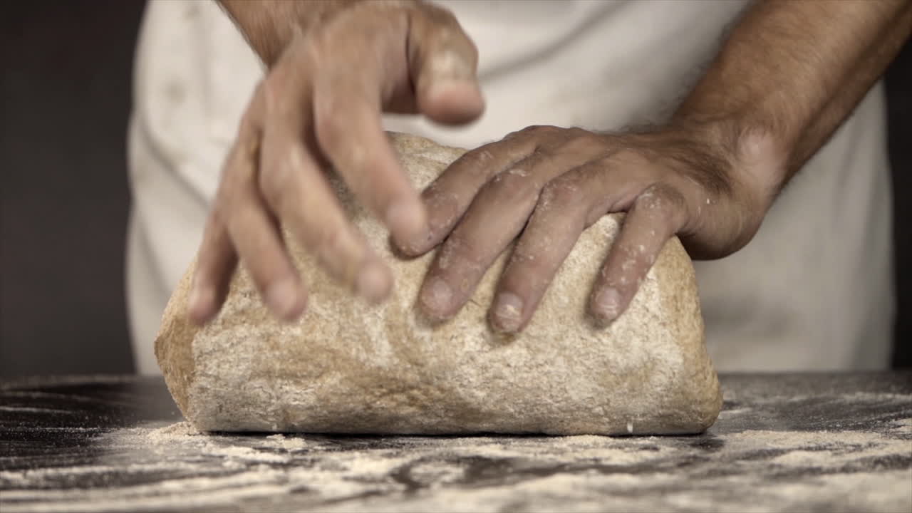 Chef's Hands Kneading Fresh Bread Dough on Floured Surface