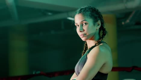 young female boxer with braided pigtails posing at ther camera while training in the gym