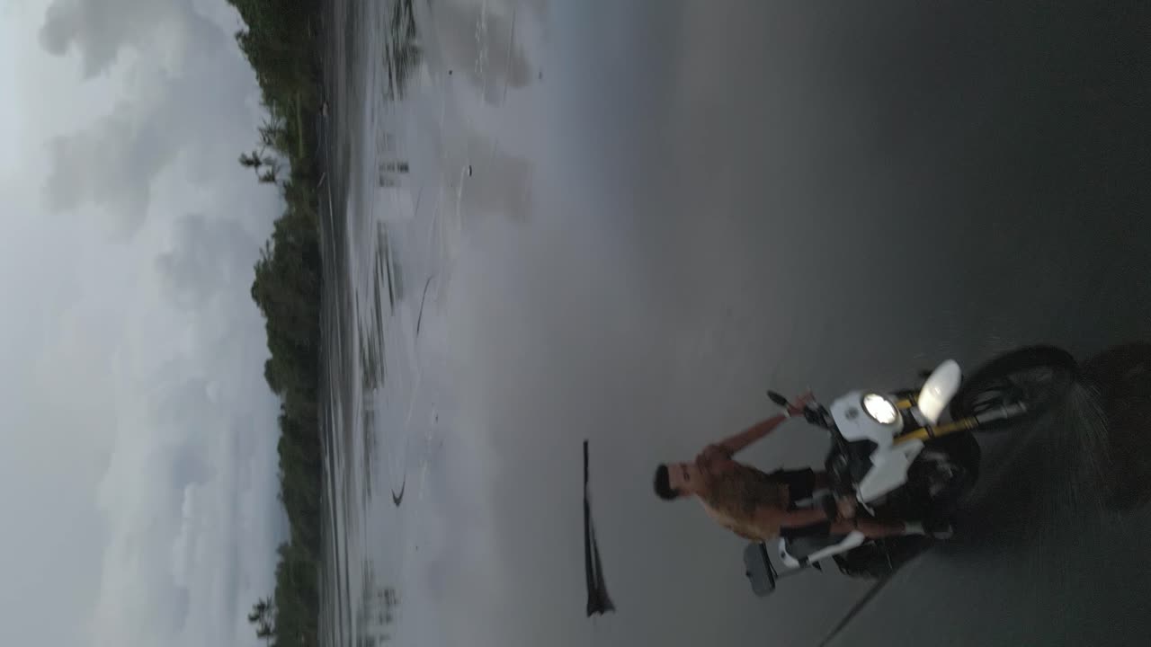 formato vertical pistas aéreas hombre asiático en la playa motocicleta de arena